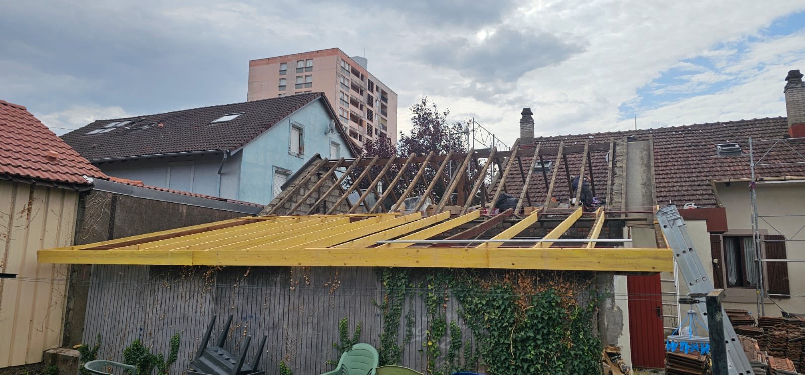 Chevronnage neuf d'un appentis, charpente principale à nu pendant une rénovation de toiture